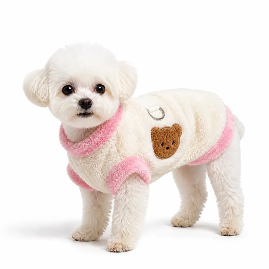 Dog wearing an ivory plush bear vest with pink trim on a pure white background