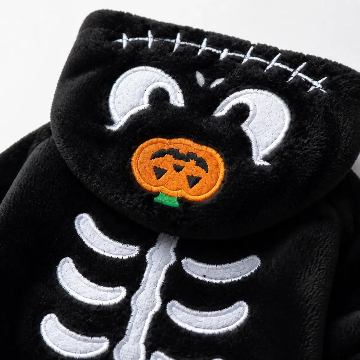 Close-up of white skeleton embroidery and orange pumpkin hood emblem